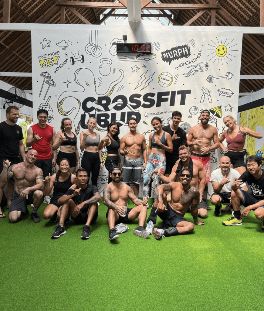 A group of people posing in front of a large sign that says "cross fit Ubud" 