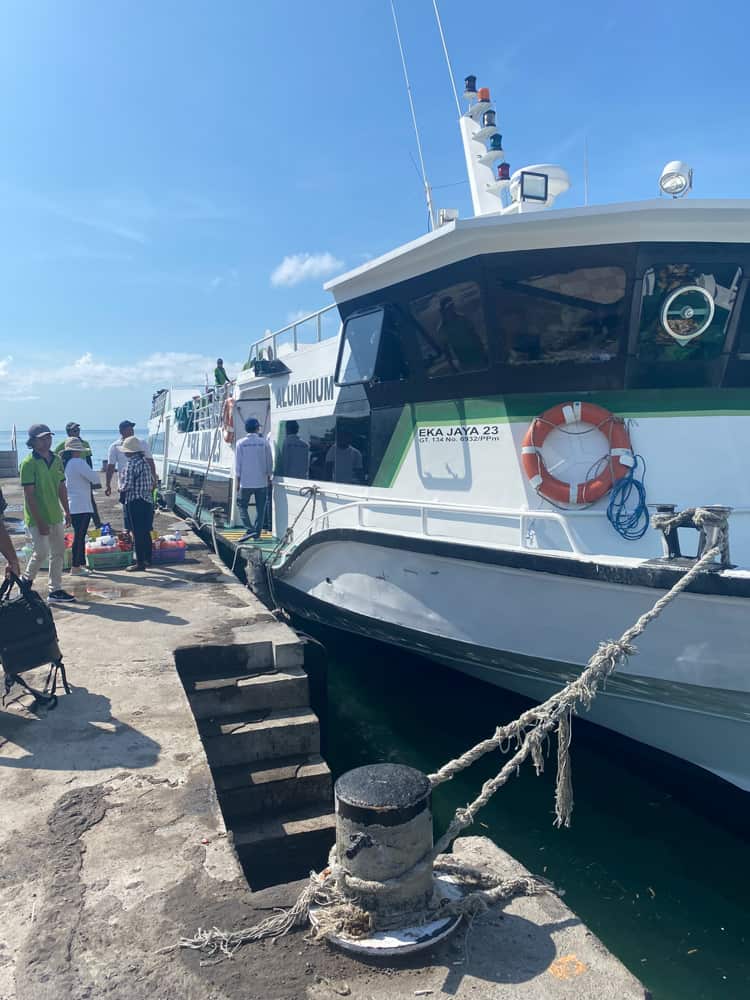 The fast boat that sails from Bali to Gili islands docked to a pier and tied with a rope. 