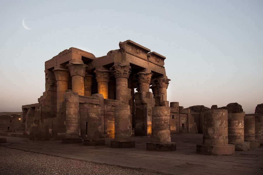Kom ombo temple in egypt at sunset with the moon peaking out from the background. Kom Ombo temple is just one of many amazing sights you can see while taking a Nile River Cruise from Cairo to Luxor and Aswan.