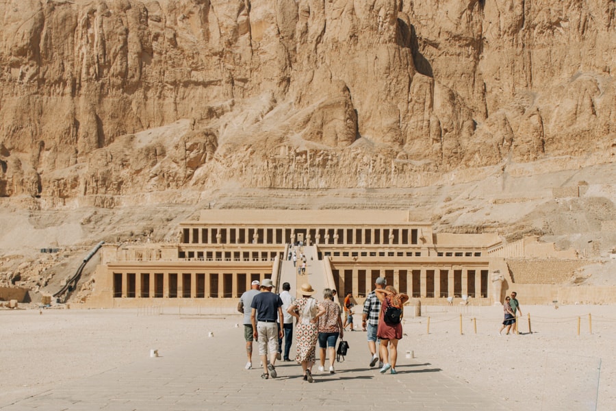 a group walking in front of the temple of Hatshepsut in the nile valley, egypt. The temple of Hatshepsut is one of many excursions people have on Nile River Cruises from Cairo to Luxor and Aswan.