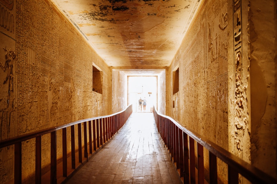 a corridor in Egypt's Valley of the Kings underground tomb. the corridor has heighroglyphics on the side of hte walls and is lit from the entry way. The Valley of the Kings is one of many excursions people have on Nile River Cruises from Cairo to Luxor and Aswan.