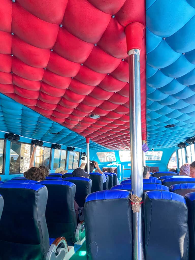 The interior of a speed boat that runs from Bali to the Gili Islands. The roof is padded and painted red and blue, you can see rows of padded seats in the interior.