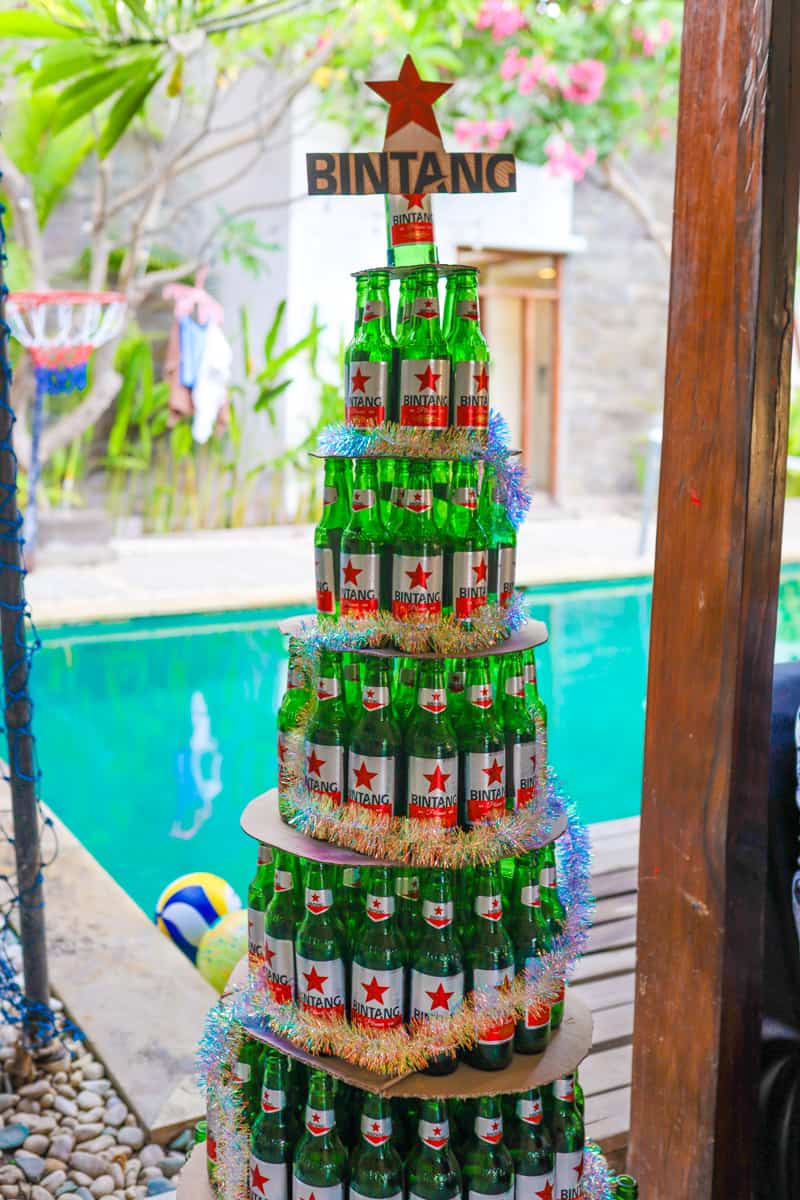 A christmas tree made up of Bintang Beer bottles in front of a swimming pool.