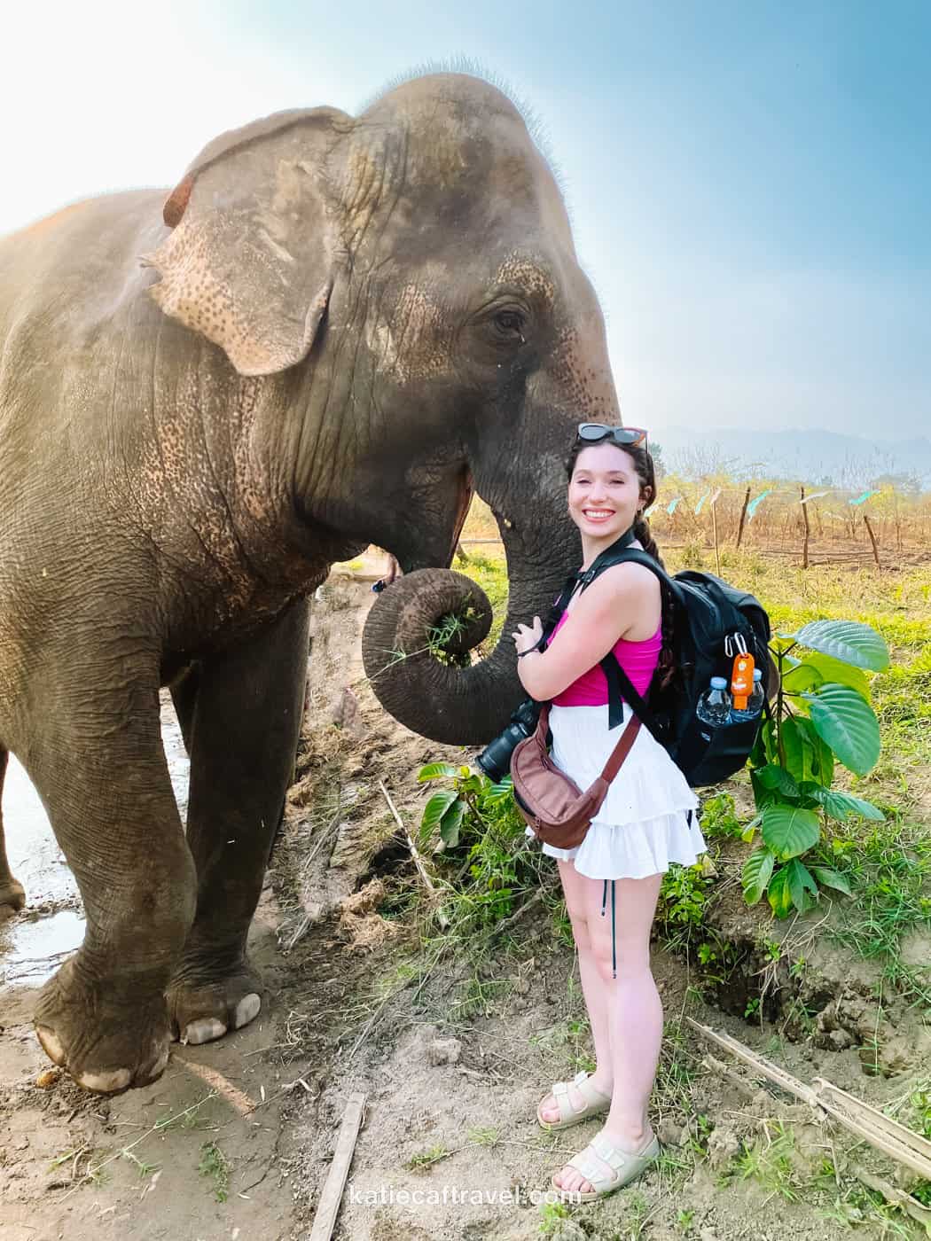 blogger Katie Caf poses next to a smiling elephant at Thom's Elephant Camp in Pai, Thailand.